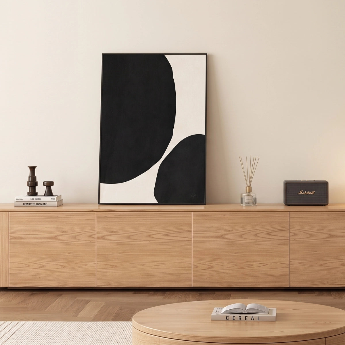 Cuadro minimalista en negro y crema apoyado sobre una credenza de madera en una sala moderna.