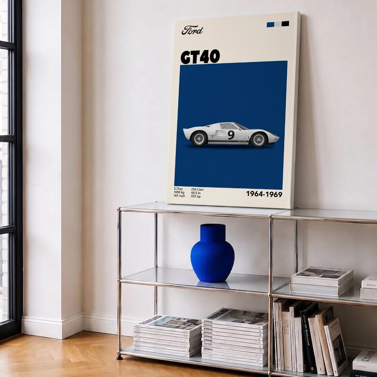 Cuadro en bastidor del Ford GT40 apoyado en una repisa metálica con florero azul en una sala moderna.