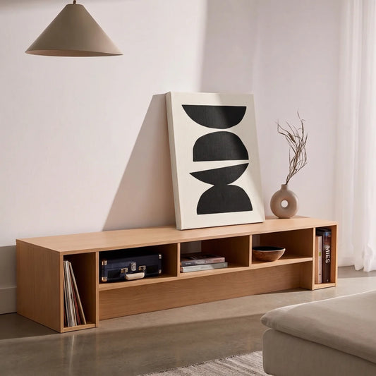 Cuadro en bastidor de arte Japandi apoyado en un mueble bajo de madera clara en un salón contemporáneo.