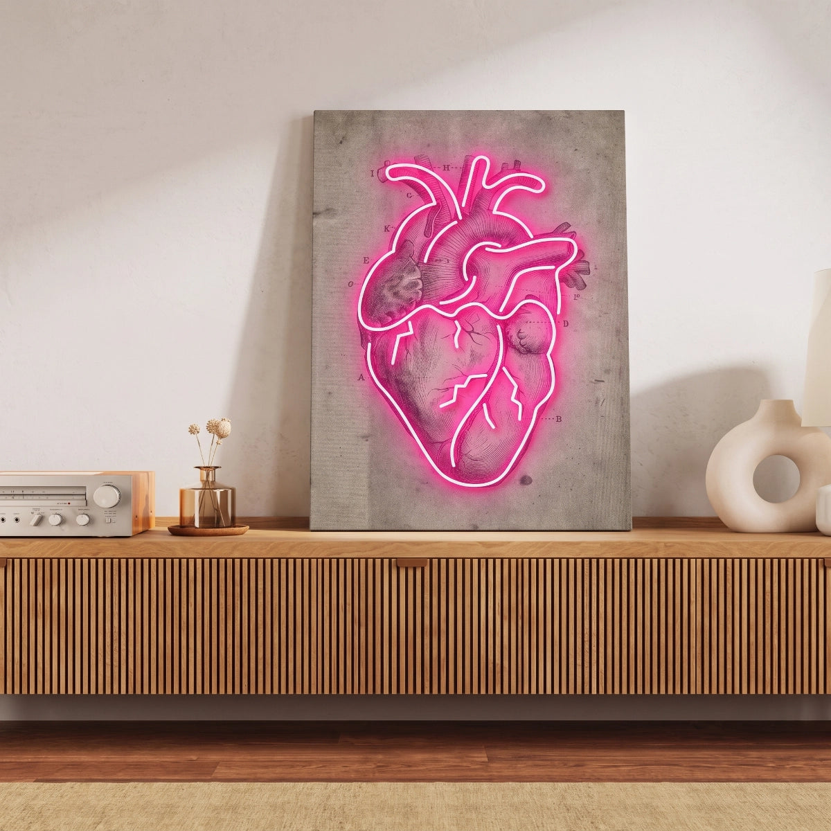 Cuadro de corazón anatómico con luz neón apoyado sobre una credenza de madera en una sala iluminada.