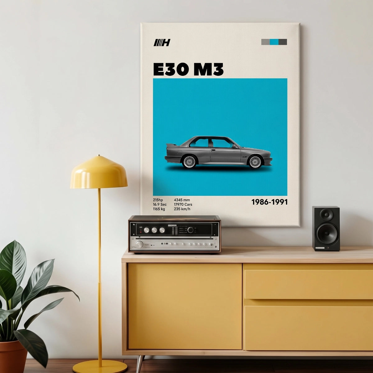 Cuadro de BMW M3 E30 colgado sobre una consola moderna con tornamesa y lámpara amarilla.