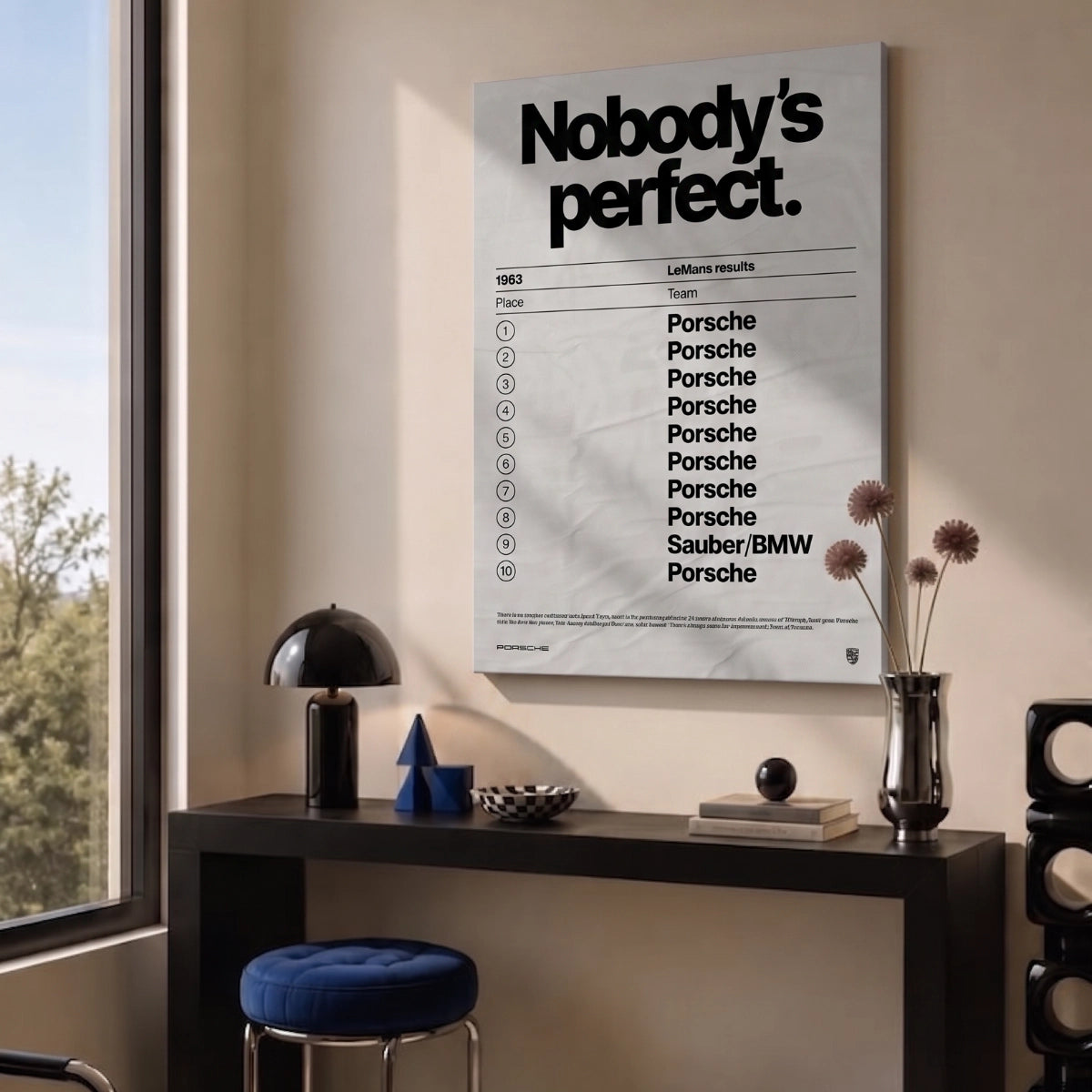Cuadro decorativo de Porsche Nobody's Perfect colgado sobre un escritorio negro en una sala moderna.